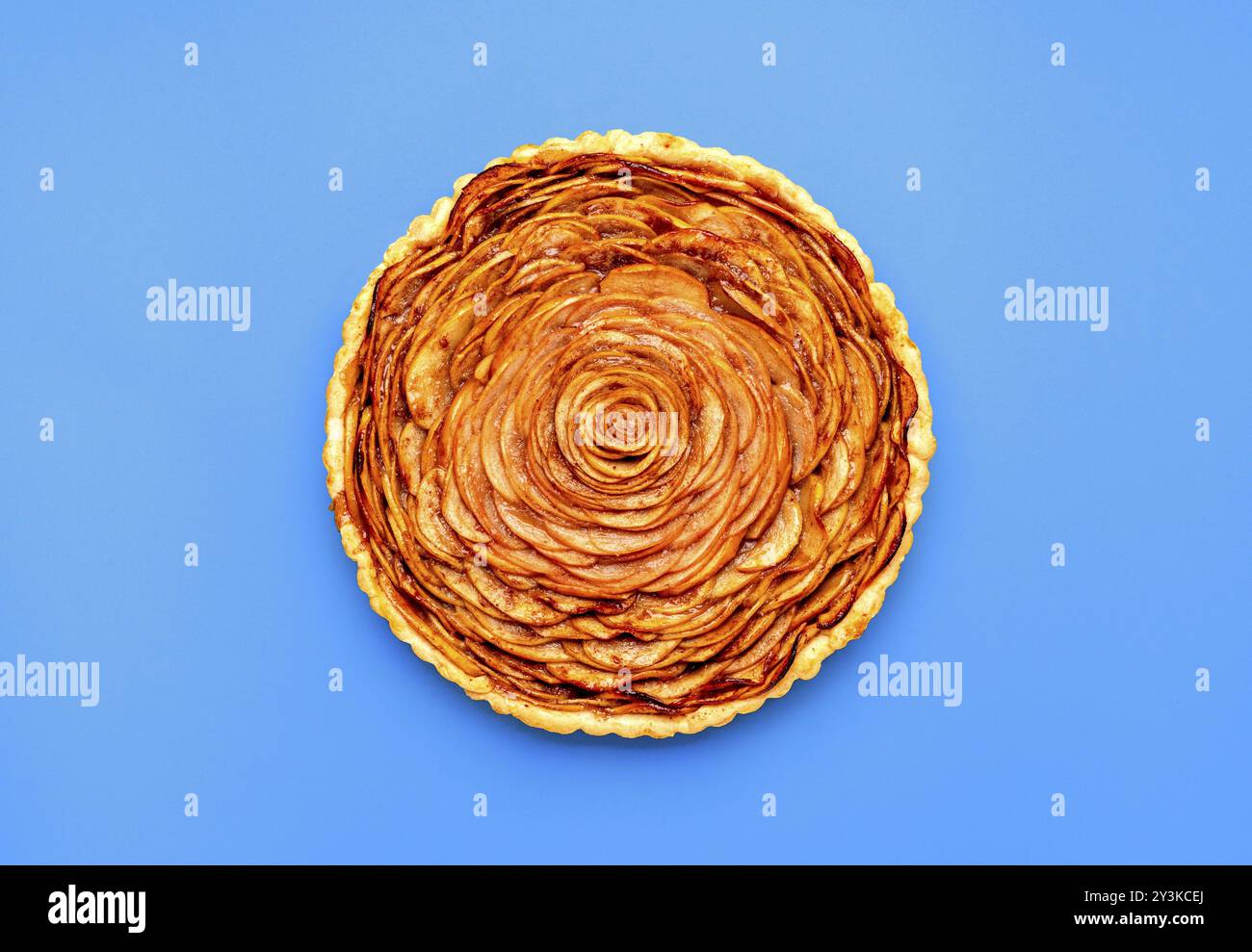 Above view with a freshly baked apple pie, minimalist on a blue table. Flat lay with a homemade apple tart Stock Photo