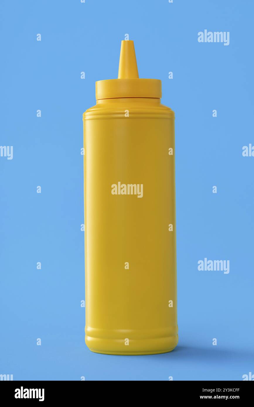 Mustard plastic bottle isolated on a blue colored background Stock Photo