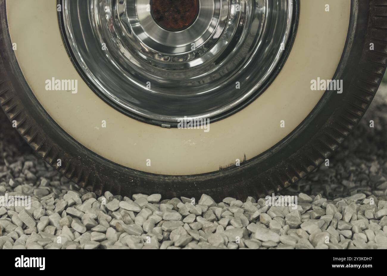 Close up with the wheel from an old timer car, details on the aged tire and the shiny chrome rim Stock Photo