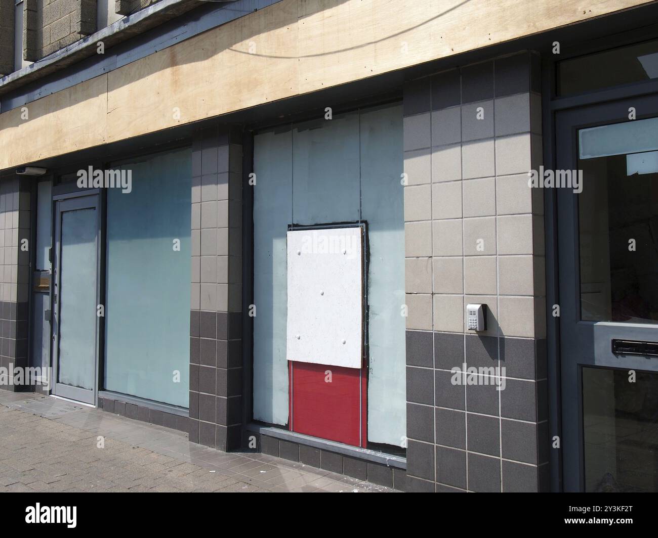 Abandoned closed high street bank or store front with boarded up and ...