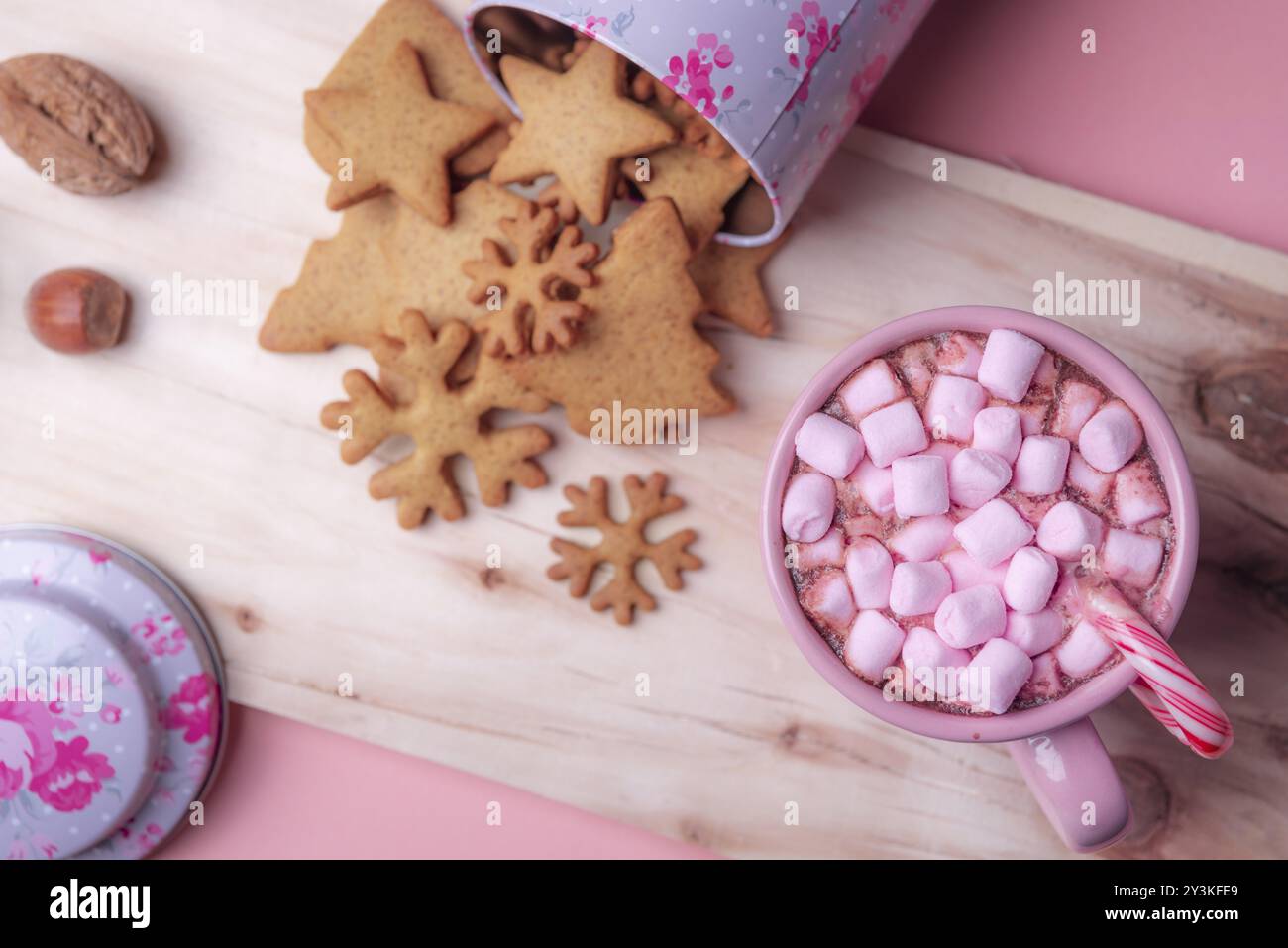 Christmas sweets context with a cup of hot cocoa with pink mini marshmallows, an overturned box with gingerbread cookies on a wooden platter Stock Photo