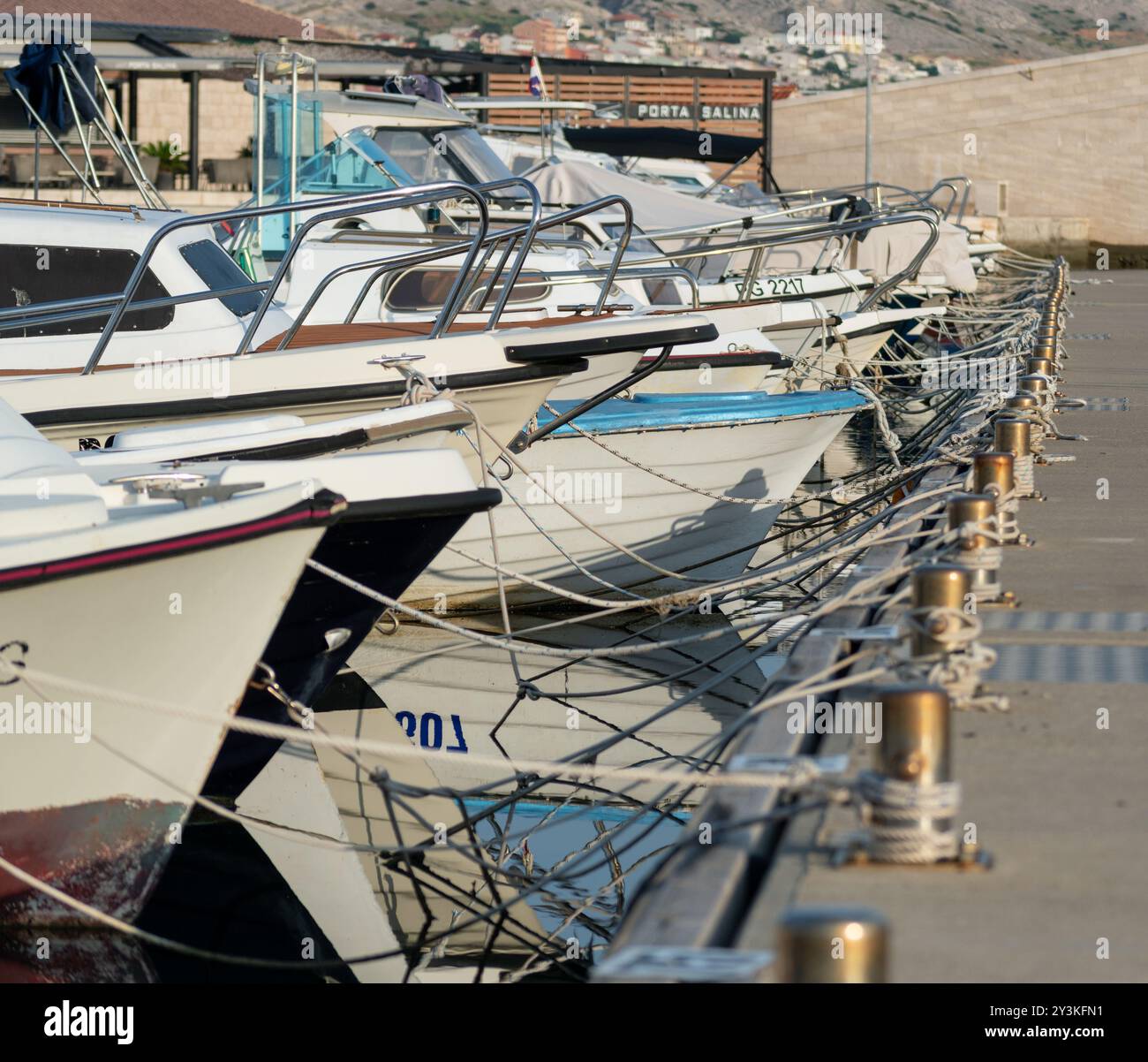 Boat bows in row moored at concrete dock Stock Photo - Alamy