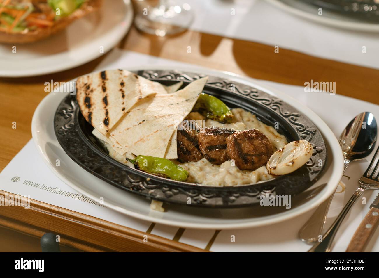 Juicy grilled meatballs served with grilled vegetables and warm flatbread on a creamy eggplant puree. A classic Middle Eastern dish. Stock Photo