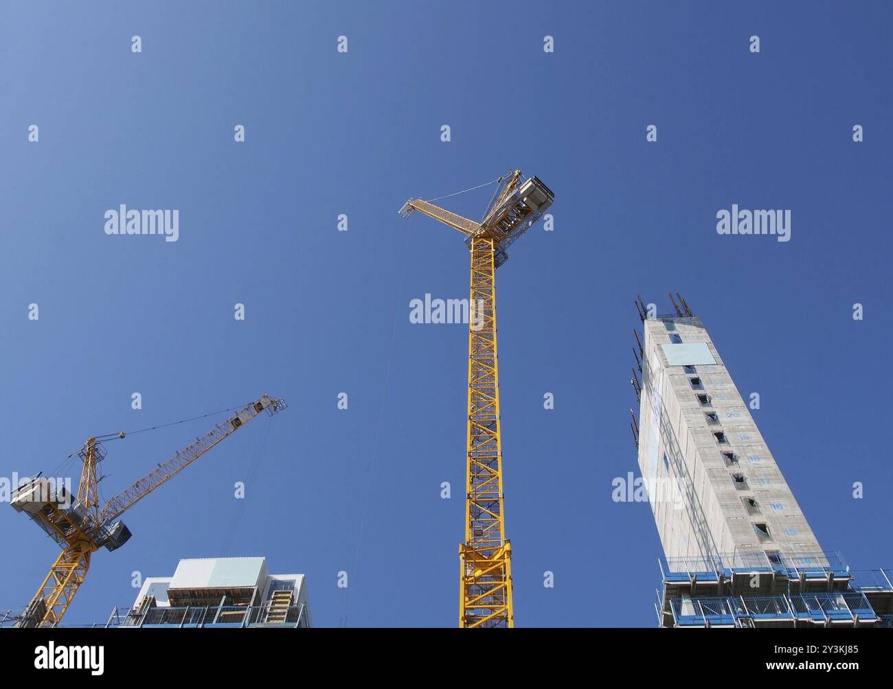 A view of tall tower cranes working on large construction sites against a blue sky in leeds england Stock Photo