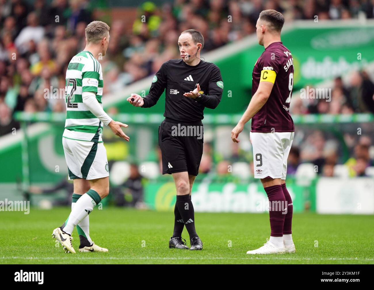 Celtic's Callum McGregor and Heart of Midlothian's James Penrice (right) with referee Colin Steven (centre) during the Scottish Premiership match at Celtic Park, Glasgow. Picture date: Saturday September 14, 2024. Stock Photo