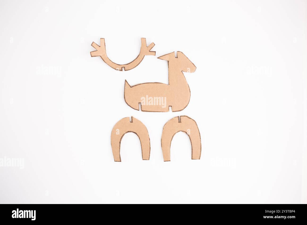 Cut-out pieces of brown cardboard on white background, showing parts for a reindeer craft project. Demonstrates recycling paper into eco friendly, cre Stock Photo