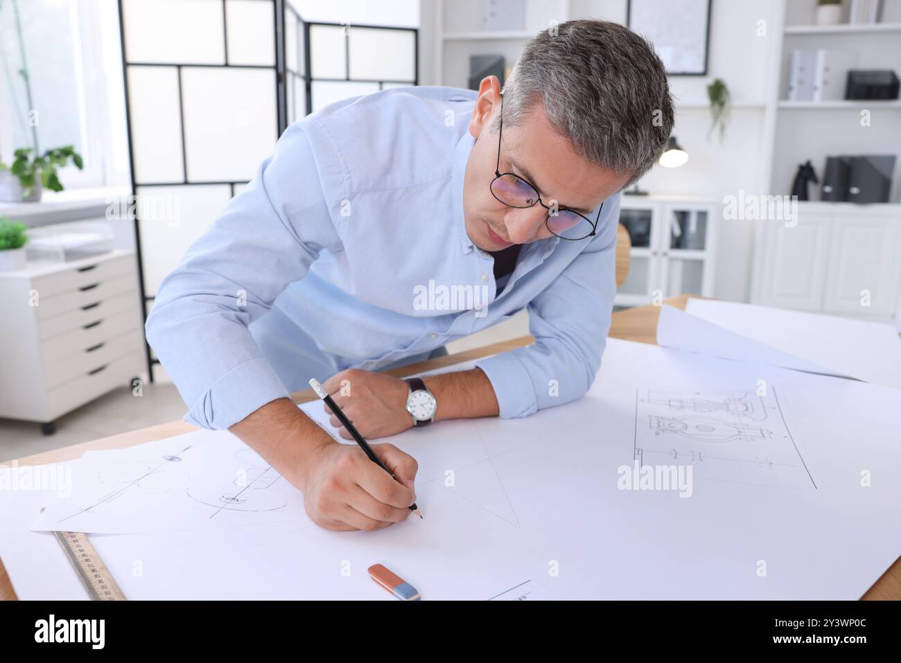 Architect making engineering drawing at table in office Stock Photo