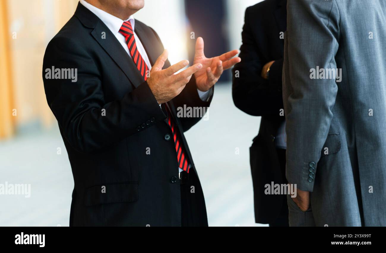 Three businessmen standing together communicating Stock Photo - Alamy