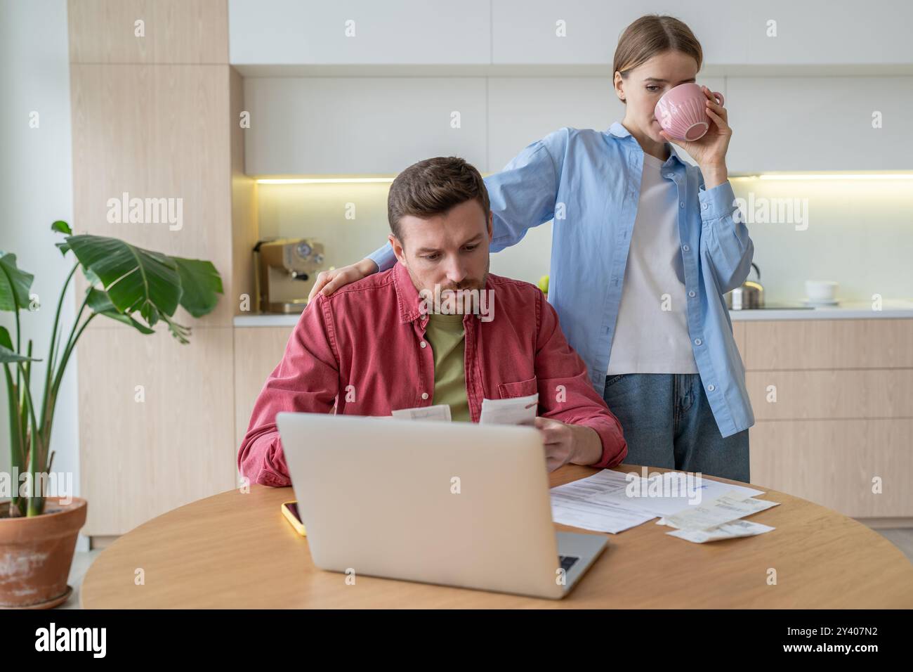 Man busy with bill calculations, taxes, rent at laptop, wife sip tea. Debt, bankruptcy, spenders Stock Photo
