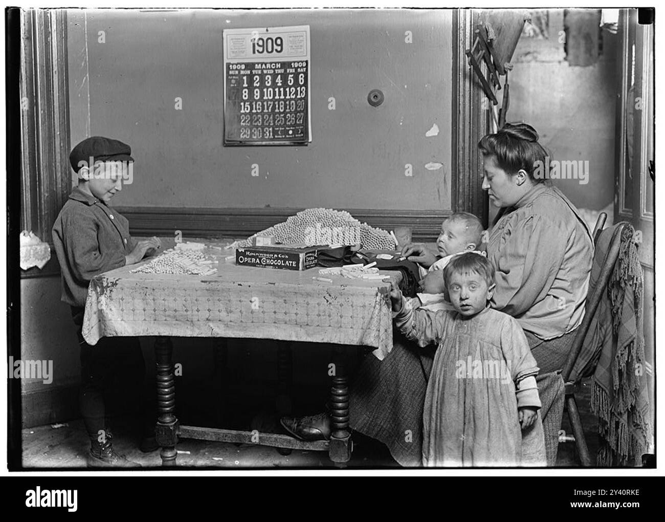 Widow & boy rolling papers for cigarettes in a dirty N.Y. tenement.  Location: New York, New York (State Stock Photo