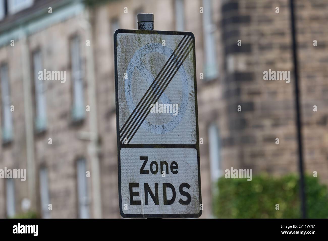 A weathered road sign indicating the end of a no parking zone, with the ...