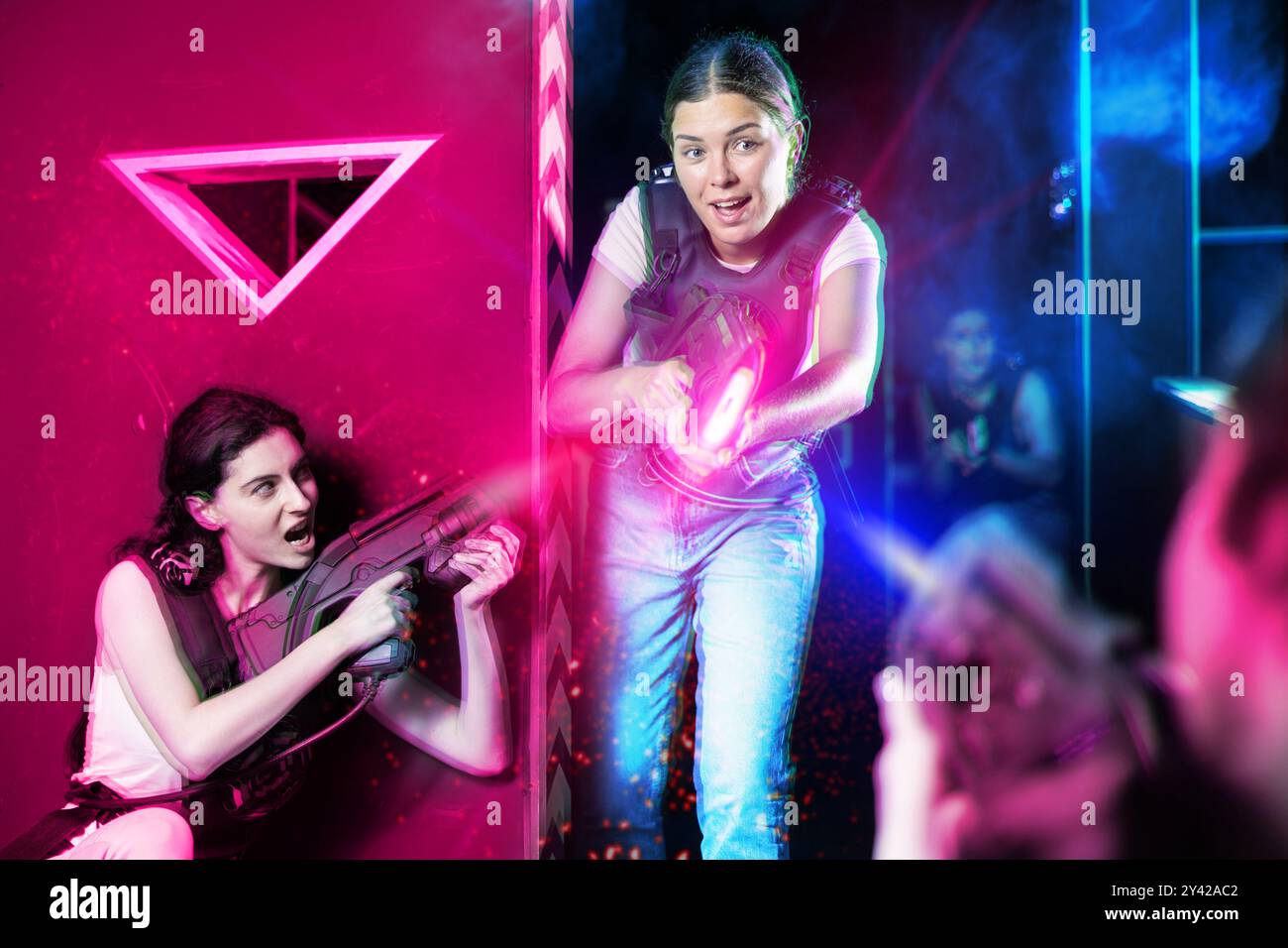 Girls play laser tag, jokingly fight with light weapons Stock Photo