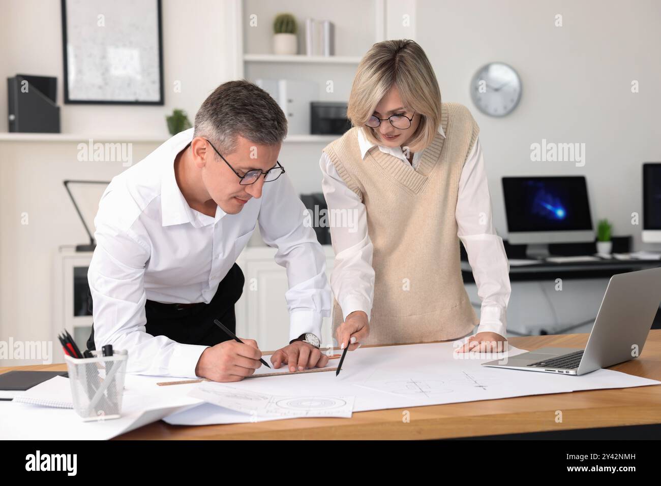 Architects making engineering drawing at wooden table in office Stock Photo