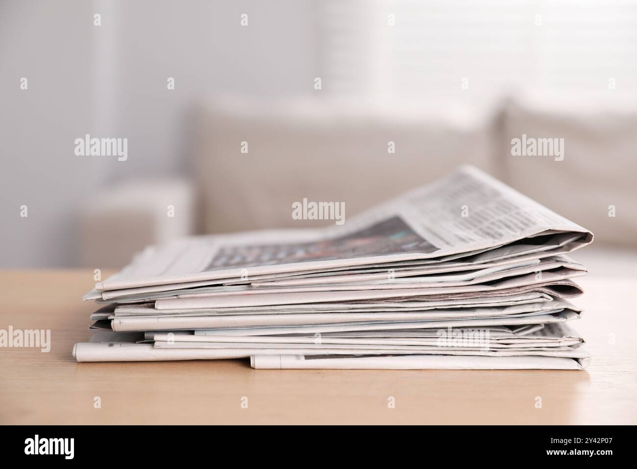 Stack of newspapers in different languages on table indoors Stock Photo