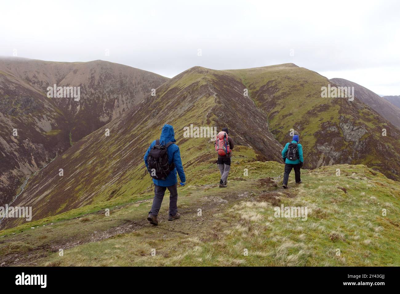 Three Men (Hikers) Walking to 'Thirdgill Head Man' from the Wainwright 'Whiteless Pike' to 'Wandope' in the Lake District National Park, Cumbria. UK. Stock Photo