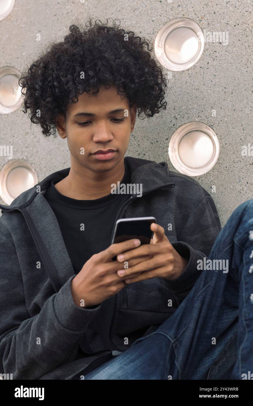 teenager with curly hair using mobile phone Stock Photo
