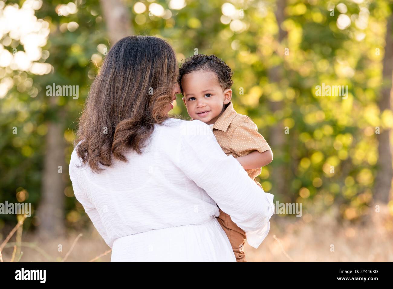 Mother holding son while he is looking over her shoulder Stock Photo