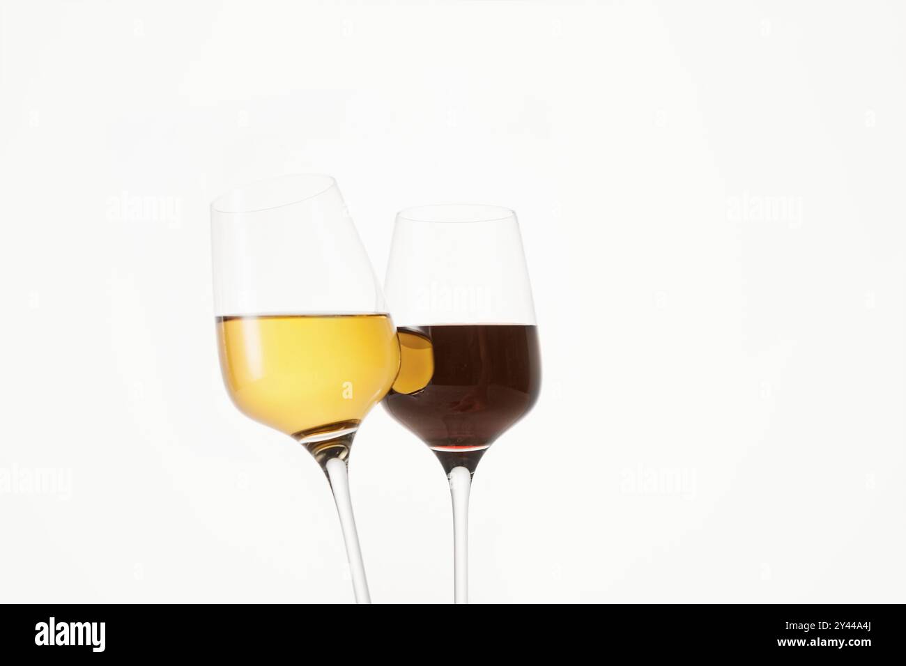 Clinking glasses on thin stems with red and white wine. Stock Photo