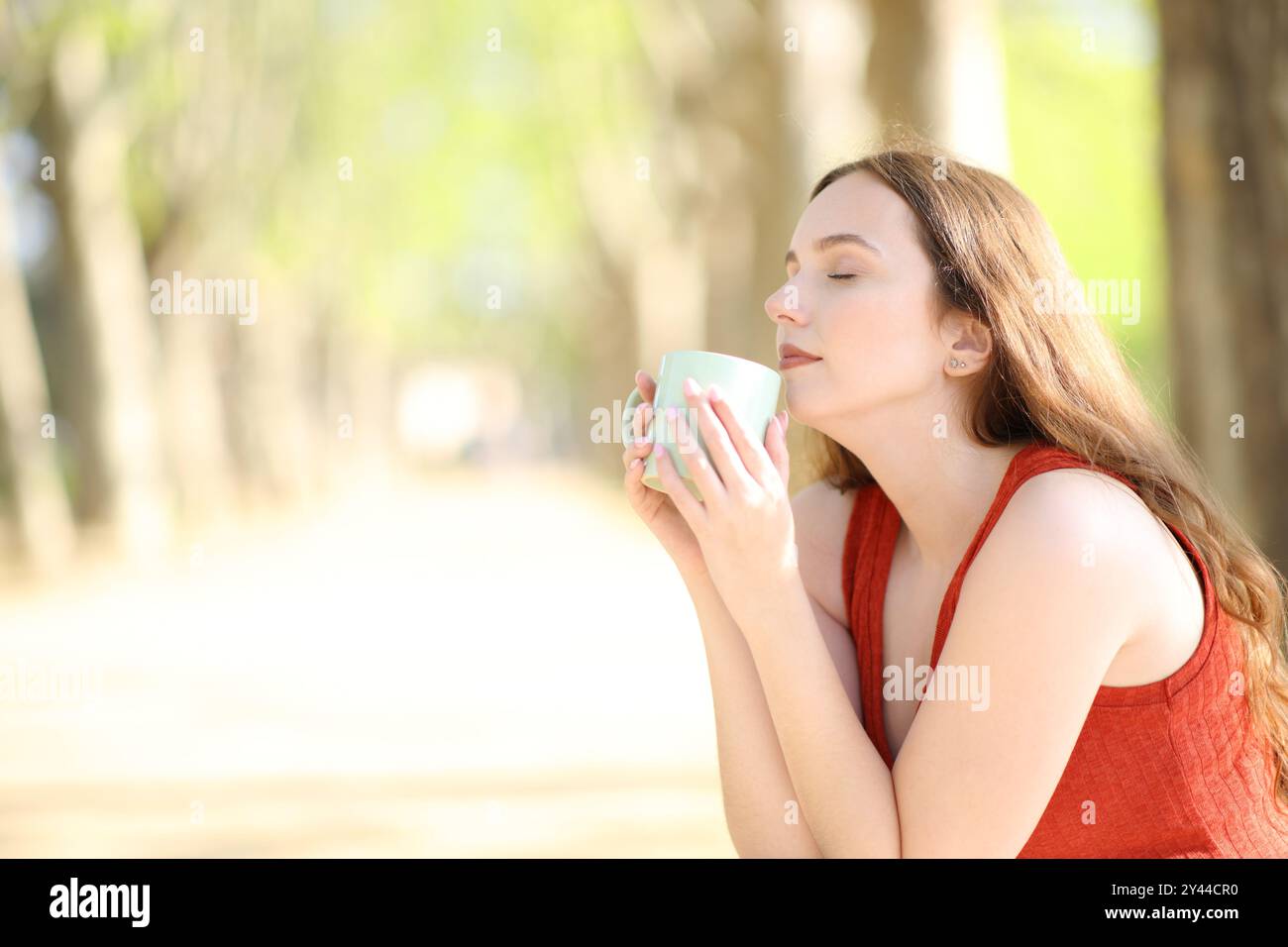 Single woman smelling coffee in a park Stock Photo - Alamy