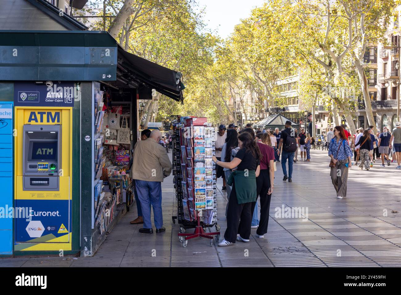 Barcelona, Spain - September 15, 2024: A busy newspaper kiosk and ATM on La Rambla, with people stopping to shop while strolling through the iconic Ba Stock Photo