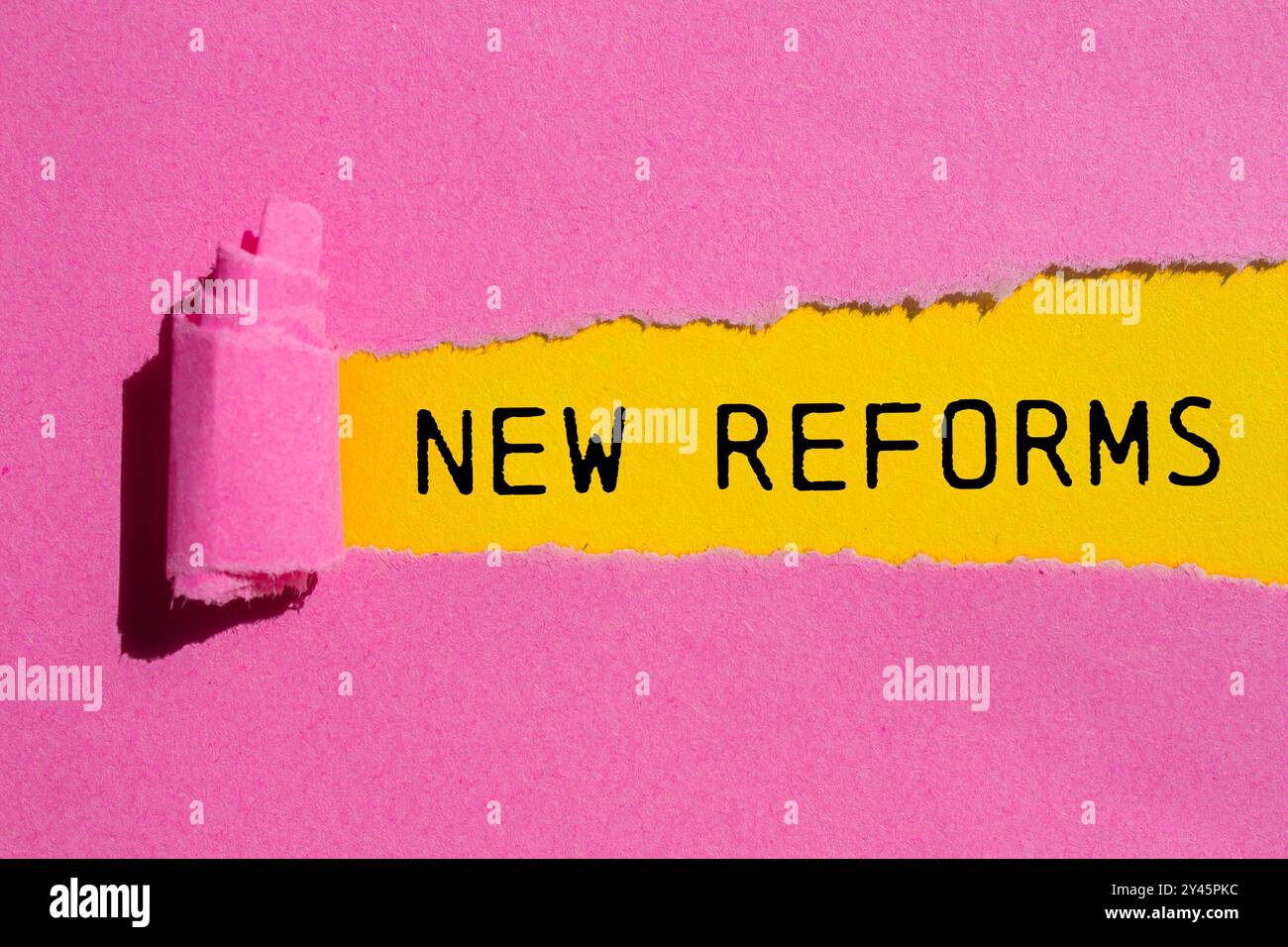 New reforms message written on ripped torn pink paper with yellow ...