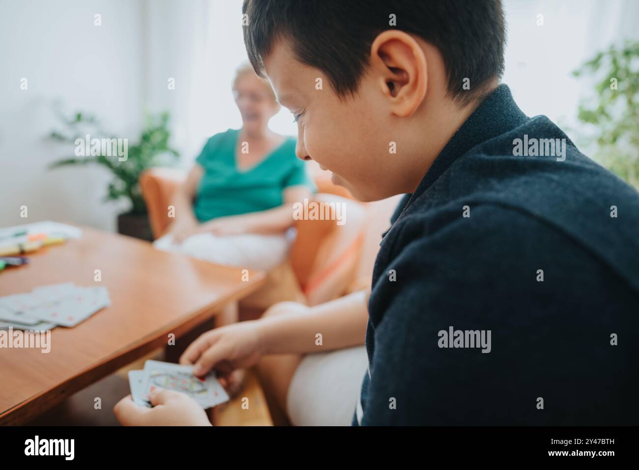 Boy playing cards with grandmother in a cozy living room setting Stock ...