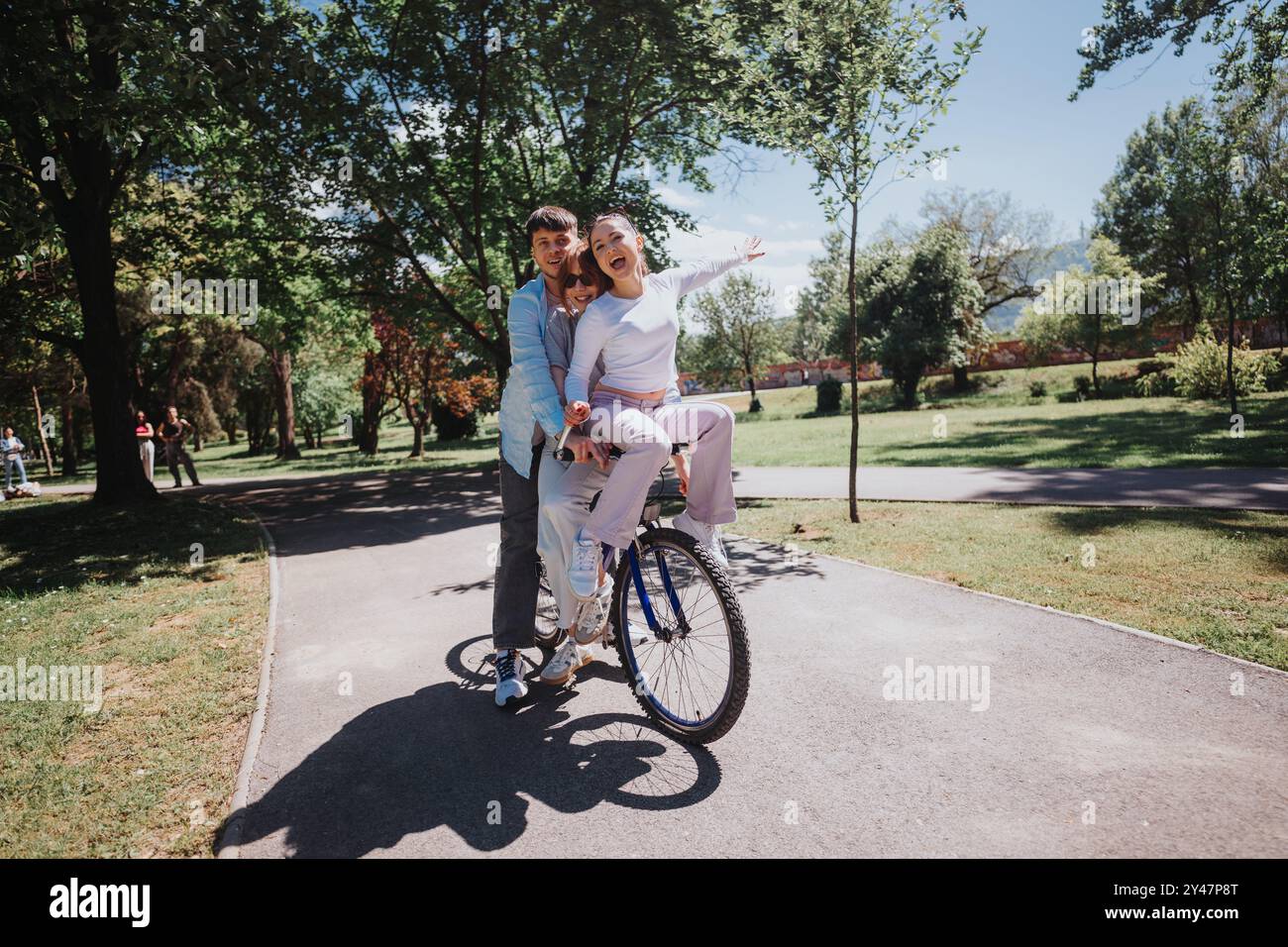 Three friends enjoying a fun bike ride in a sunny park on a weekend ...