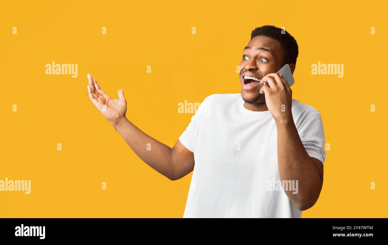Surprised black guy talking on the phone and gesturing Stock Photo