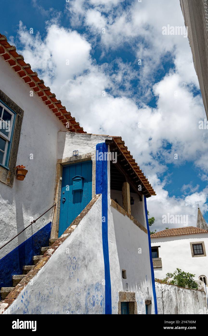 Bright blue accents frame a traditional house under a sunny sky in the charming town of center Stock Photo