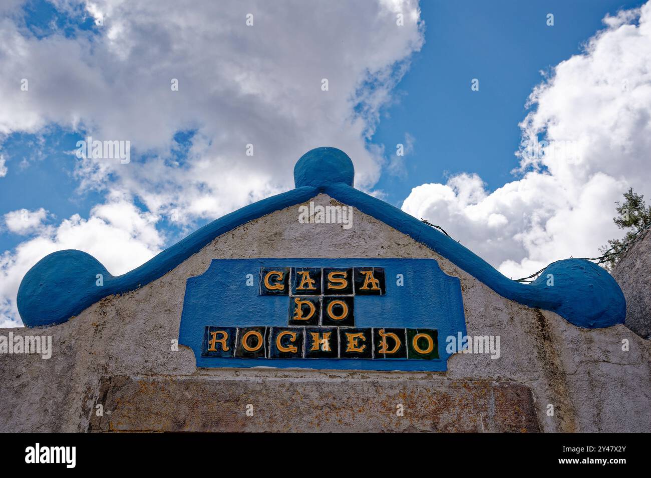 Bright blue accents and traditional tiles mark the casa do rochedo under the Óbidos vibrant sky Stock Photo