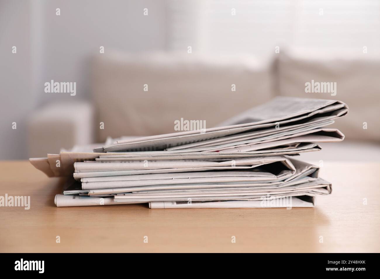 Stack of newspapers in different languages on table indoors Stock Photo