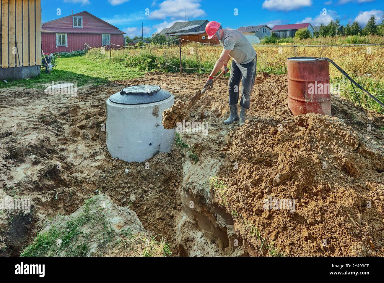 Builder fills an absorbent trench in wastewater plumbing with sand by hand, using bayonet shovel. Stock Photo