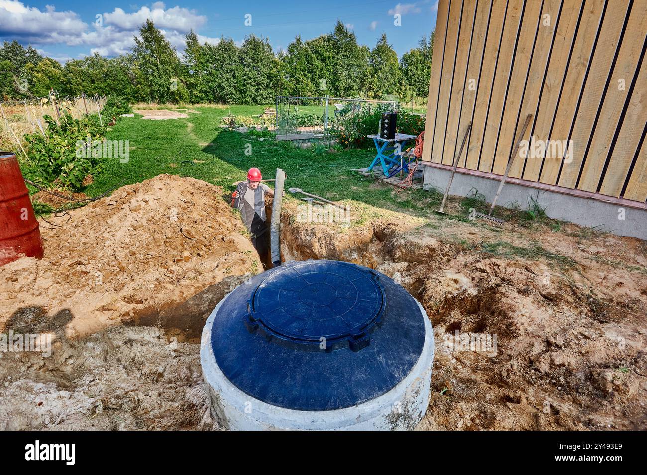 Laying drainage fabric and perforated pipe in an absorption trench for wastewater plumbing. Stock Photo