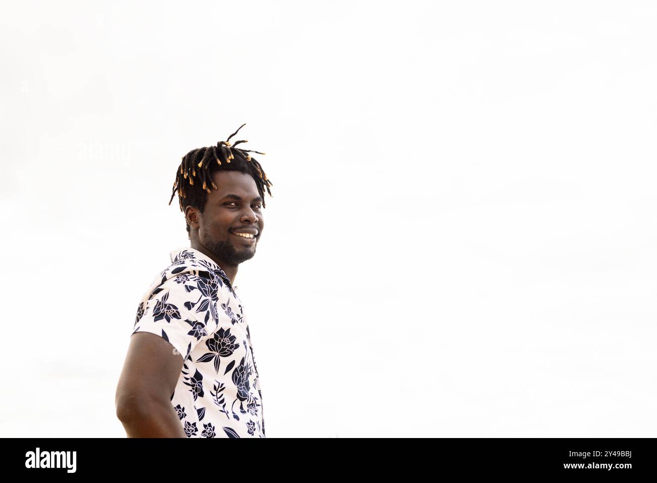 stylish young black man with flower shirt smiling Stock Photo