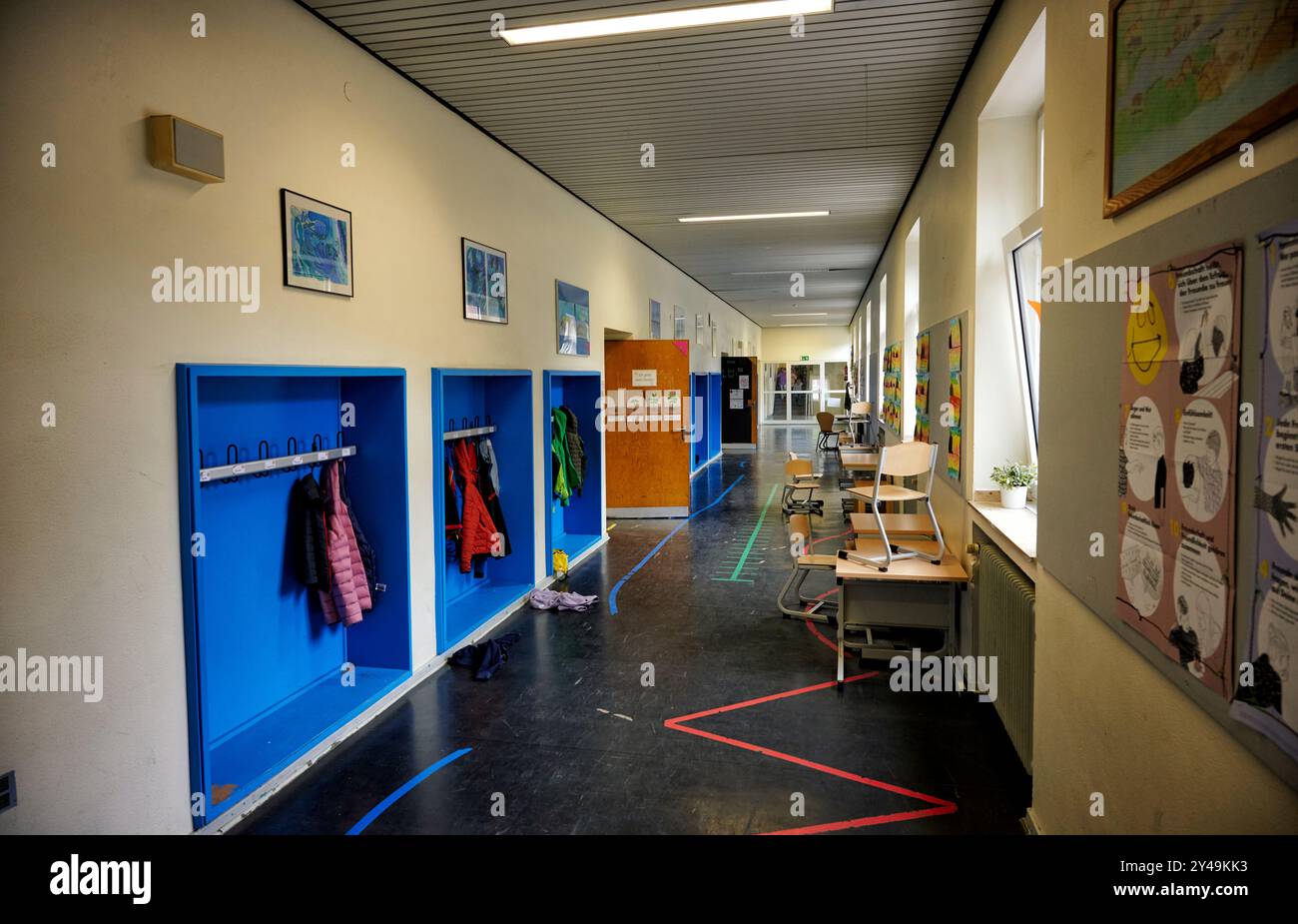 Ein Gang in einer Essener Grundschule. Zu sehen sind blaue Garderoben in dem Jacken und andere Beutel und Kleidungsstücke hängen die zum Teil rot sind Stock Photo