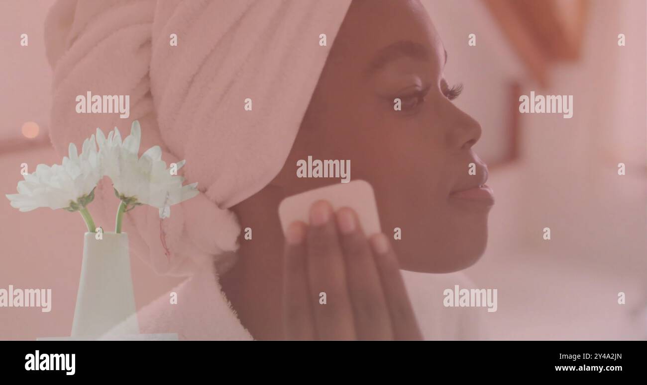 Image of white flowers in vase over happy african american woman cleansing face in bathroom Stock Photo