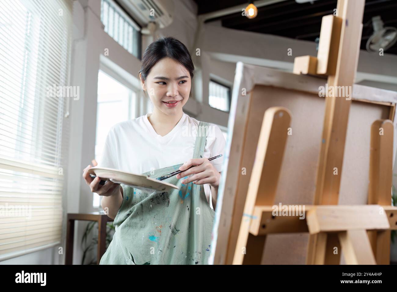 Young Female Artist Painting on Canvas in a Bright Studio with Natural ...