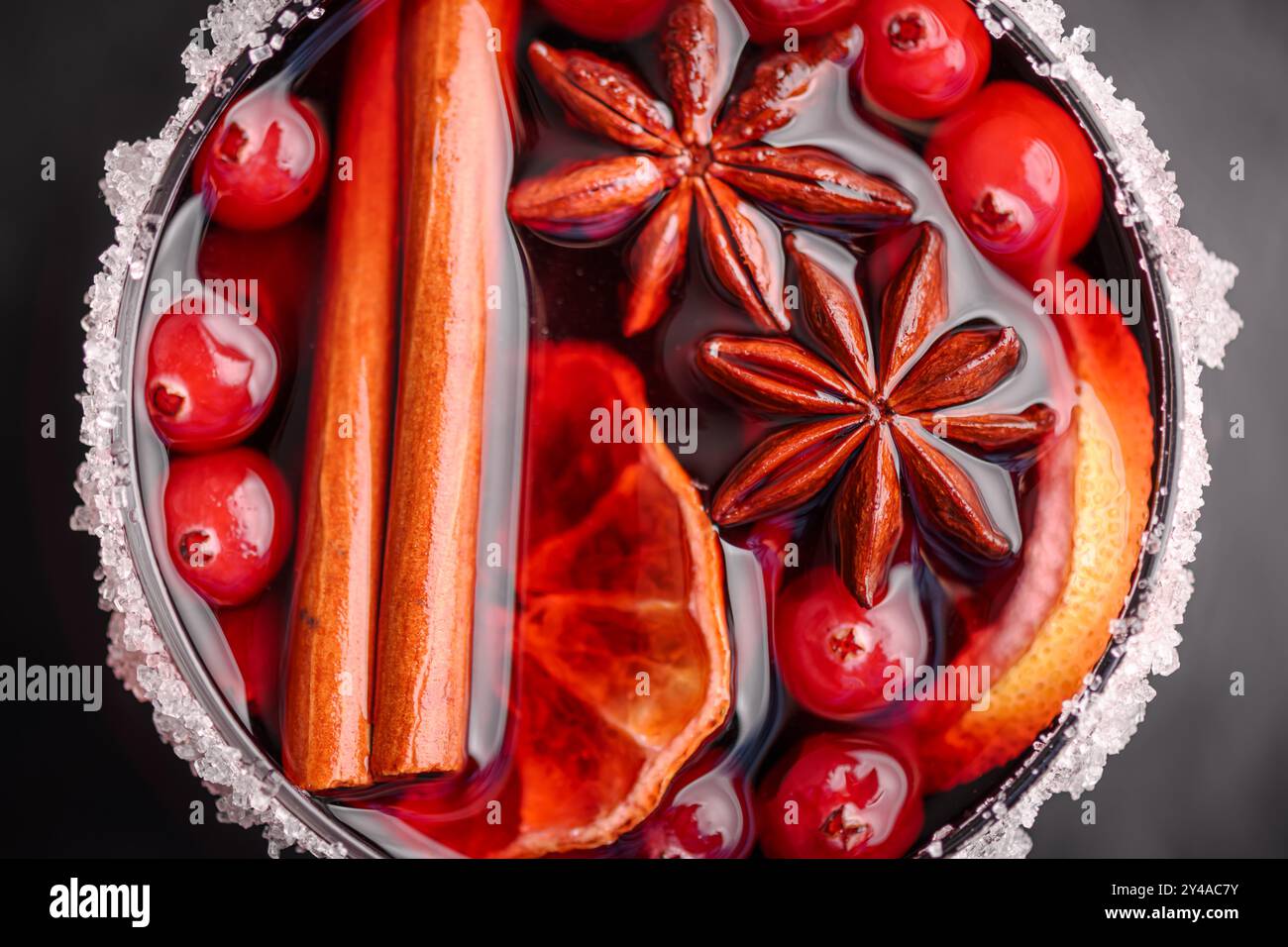 Red mulled wine in glass with slices of orange, cinnamon stick, star anise and cranberries on black background close up. Food photography Stock Photo