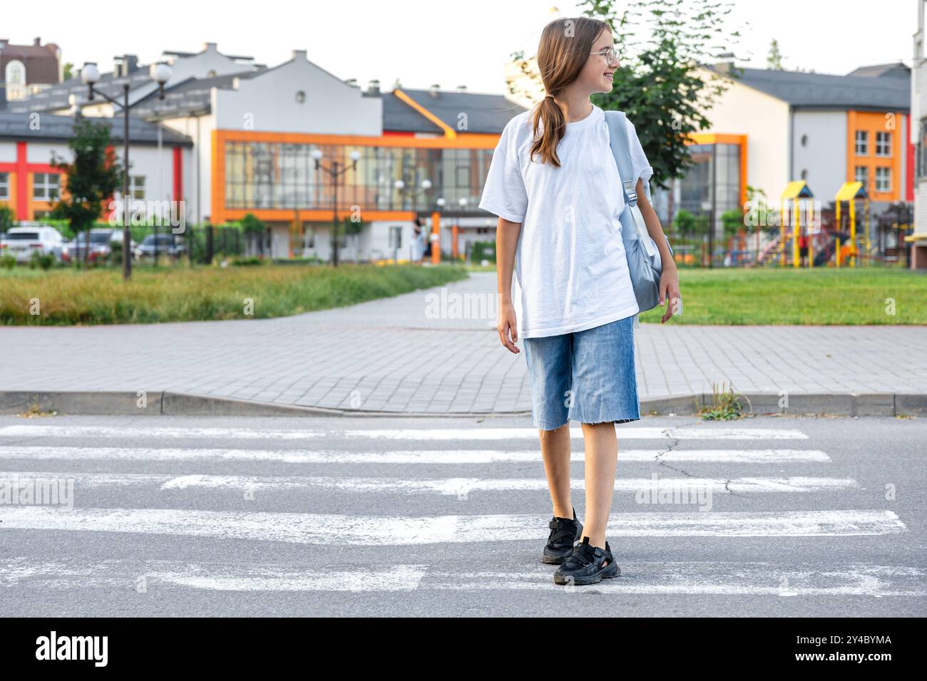 The girl goes to school. A schoolgirl crosses a pedestrian crossing ...