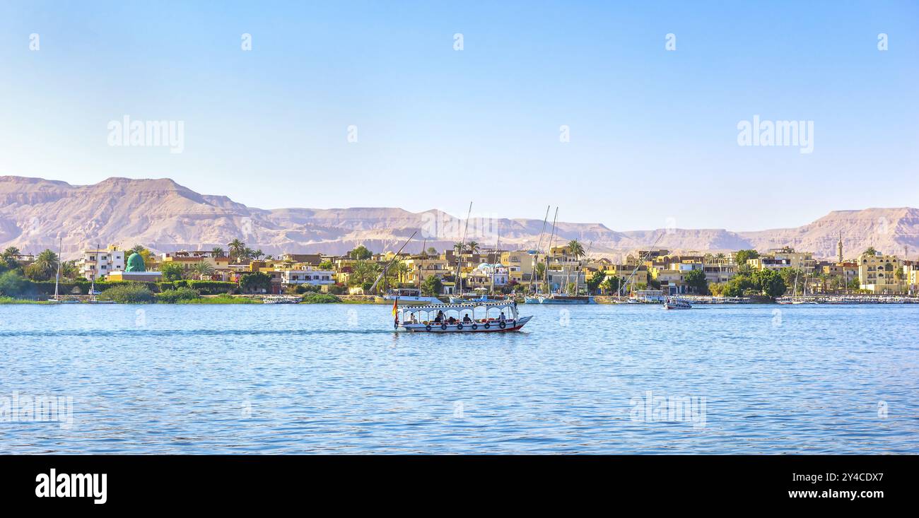 Touristic boat floating past the village on river Nile in Luxor, Egypt ...