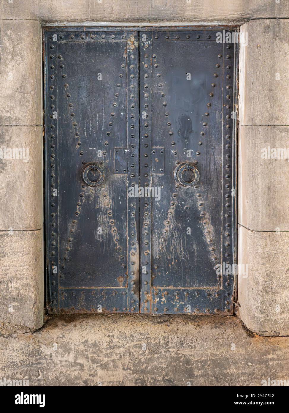 Steel industrial doors with rivet patterns and forged loop pulls set in concrete block opening Stock Photo