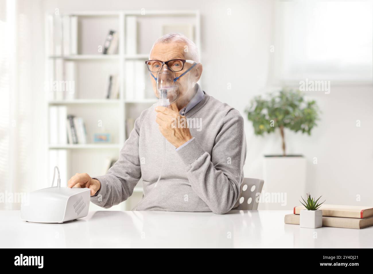 Senior man sitting at home and using a nebulizer Stock Photo