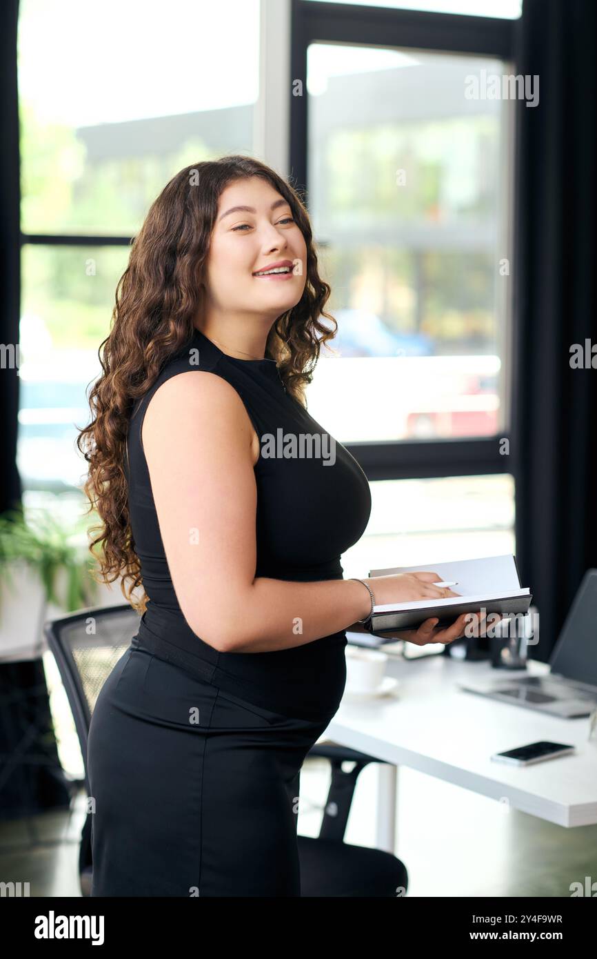 A young and beautiful plus size woman stands confidently in her stylish office, engaging in productive work. Stock Photo