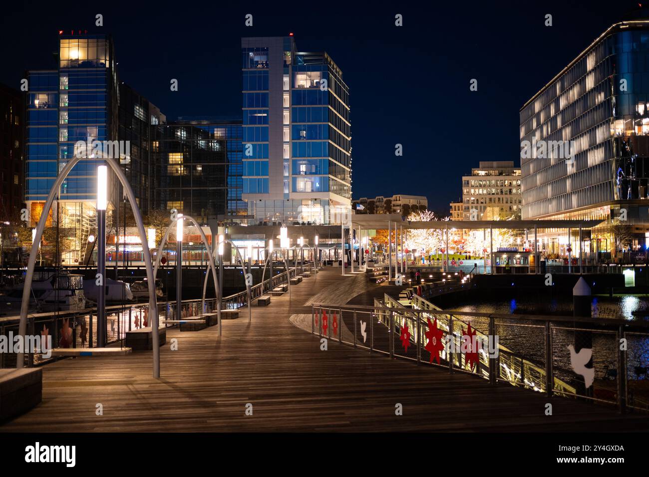 The Wharf Holiday Lights Washington DC // WASHINGTON DC — The Wharf, a vibrant waterfront neighborhood in Washington DC, is illuminated with festive holiday lights at night. The colorful display reflects off the Washington Channel, creating a magical winter scene along the Potomac River and showcasing the area's blend of modern development and seasonal charm. Stock Photo