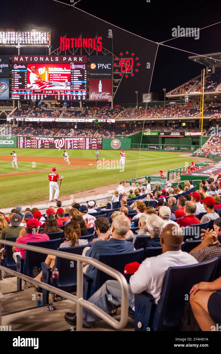 Nationals Park Baseball Game Washington DC // WASHINGTON DC — A view from the stands behind home plate during a night baseball game at Nationals Park between the Washington Nationals and the St. Louis Cardinals. The stadium lights illuminate the field as fans watch the MLB action under the night sky. Stock Photo