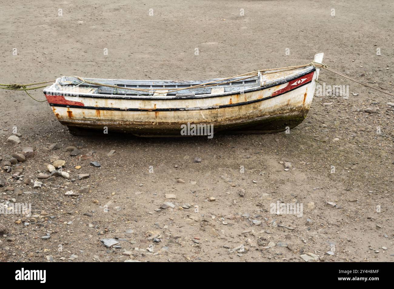 Old traditional coastal fishing boat moored up on beach at low tide in ...