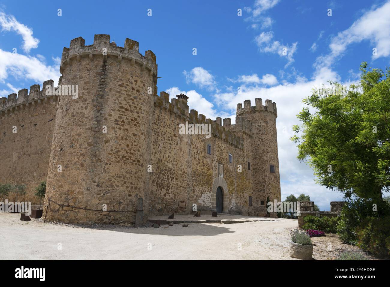 Historic stone castle with towers in front of a sunny sky with clouds, near trees, Castillo de las Arguijuelas de Arriba, Caceres, Caceres, Extremadu Stock Photo