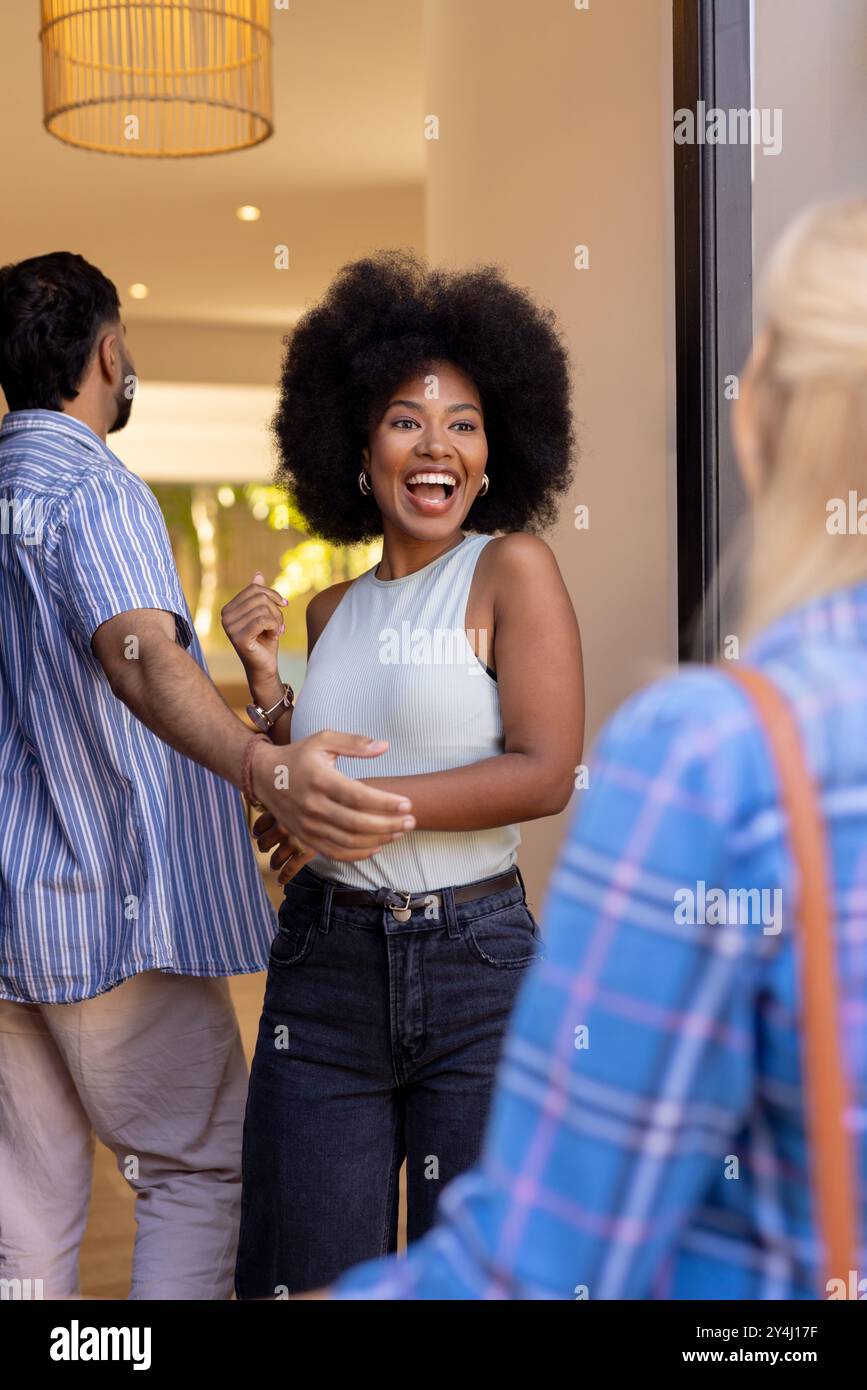 Greeting friends at doorway, woman smiling and hugging man in casual clothes Stock Photo