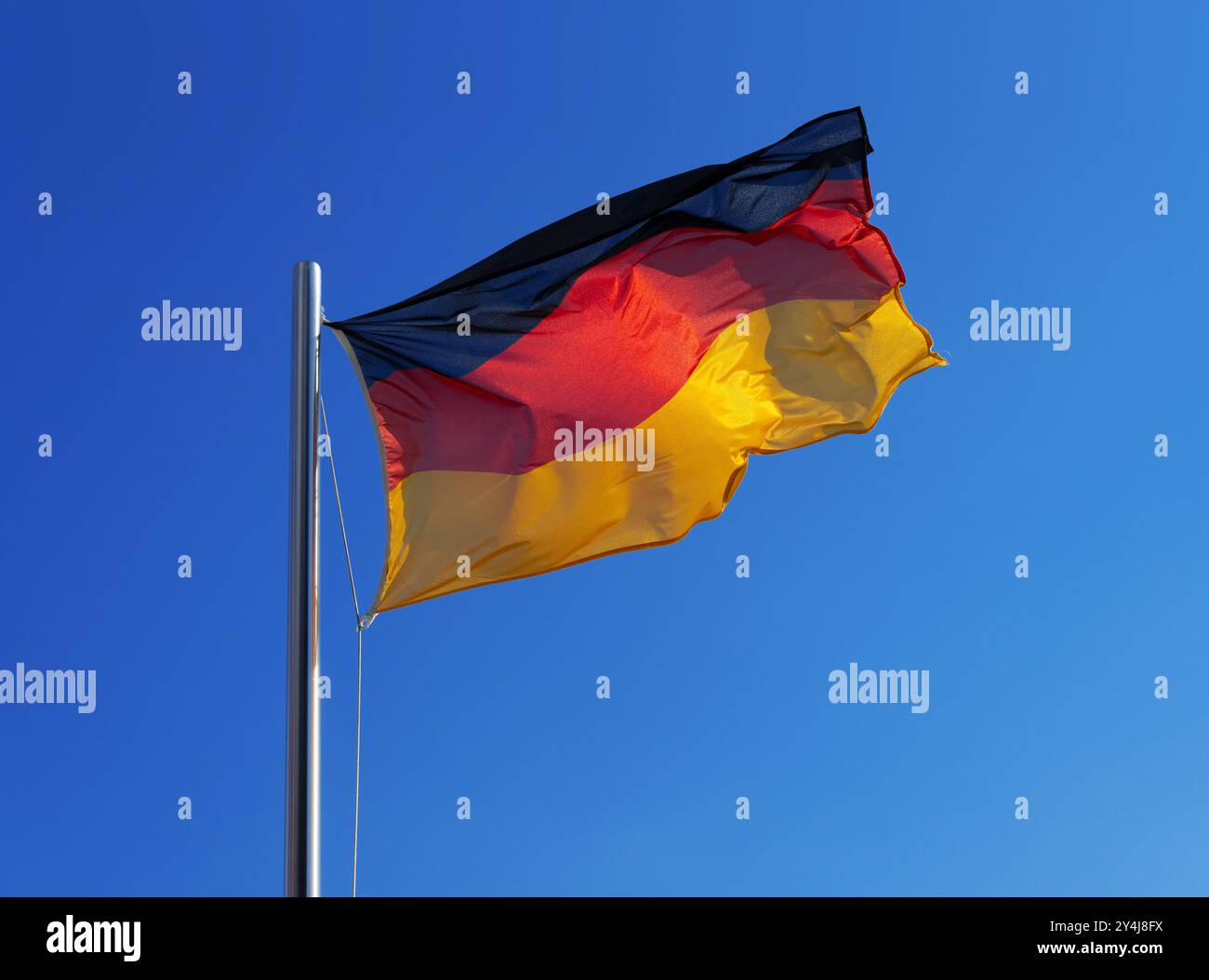 German national flag in strong wind against blue sky Stock Photo