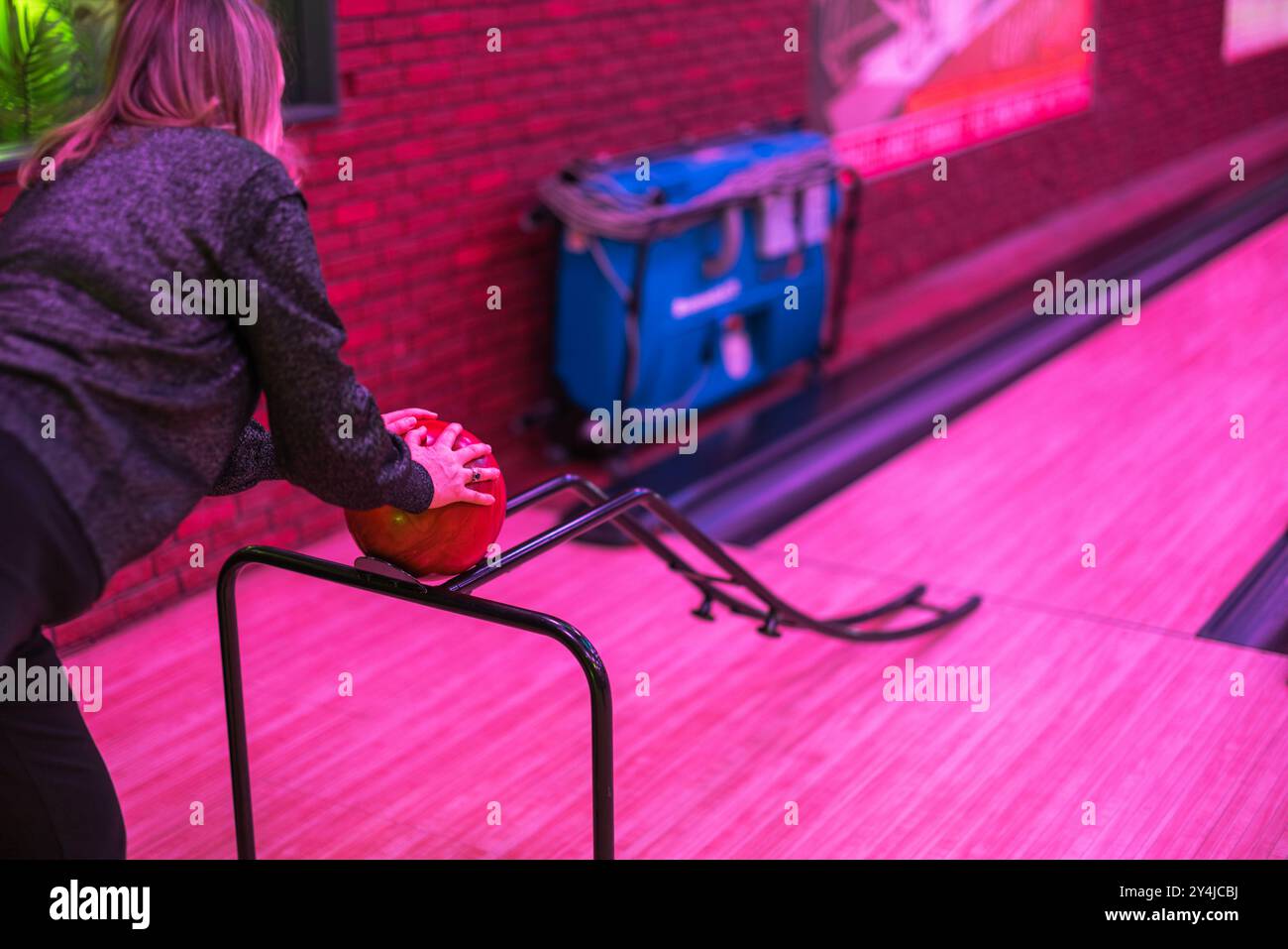 Bowling alley scene with woman placing bowling ball on ramp for smaller ...